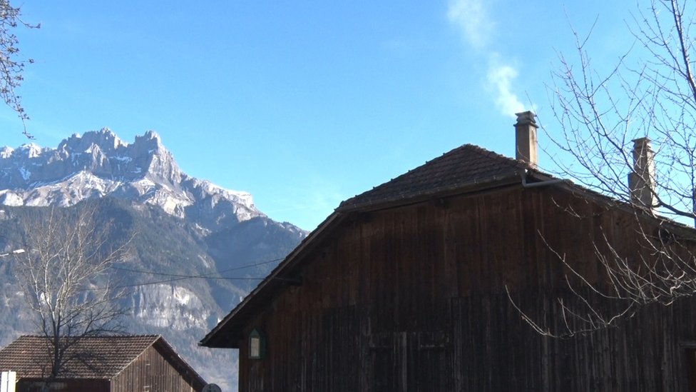 Casa alpina y humo saliendo de la chimenea