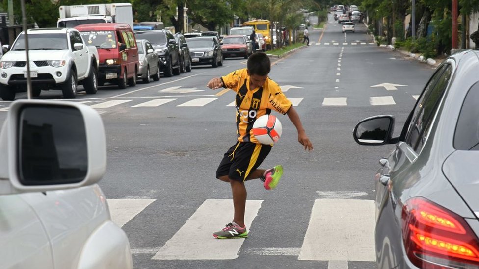 Un niño jugando con un balón en una calle de Asunción