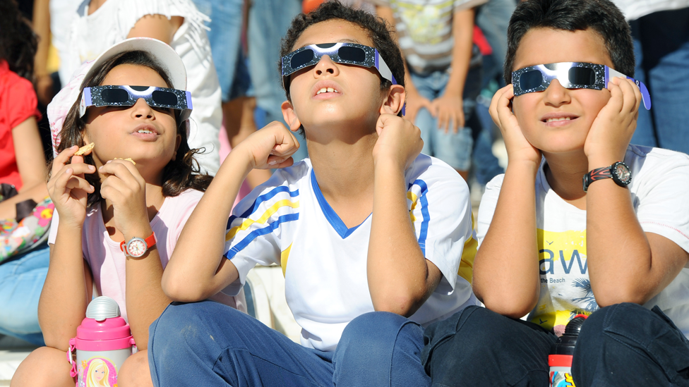Niños viendo un eclipse con lentes especiales
