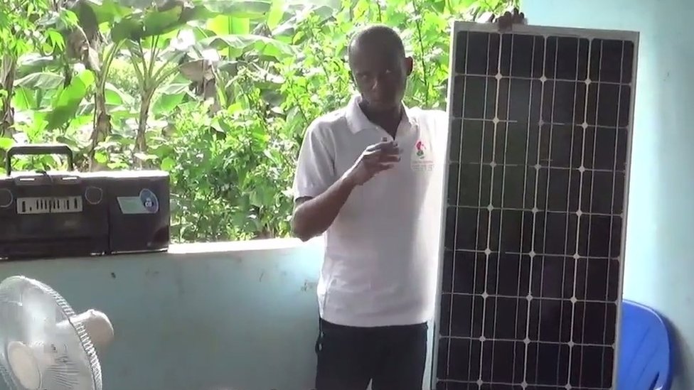 Man explaining how solar panels work to villagers