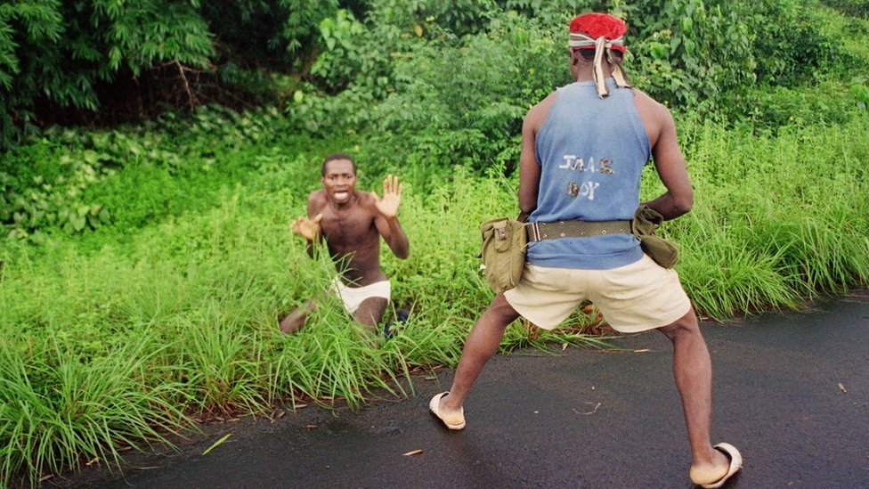 Gunman confronts a man during Liberia's civil war