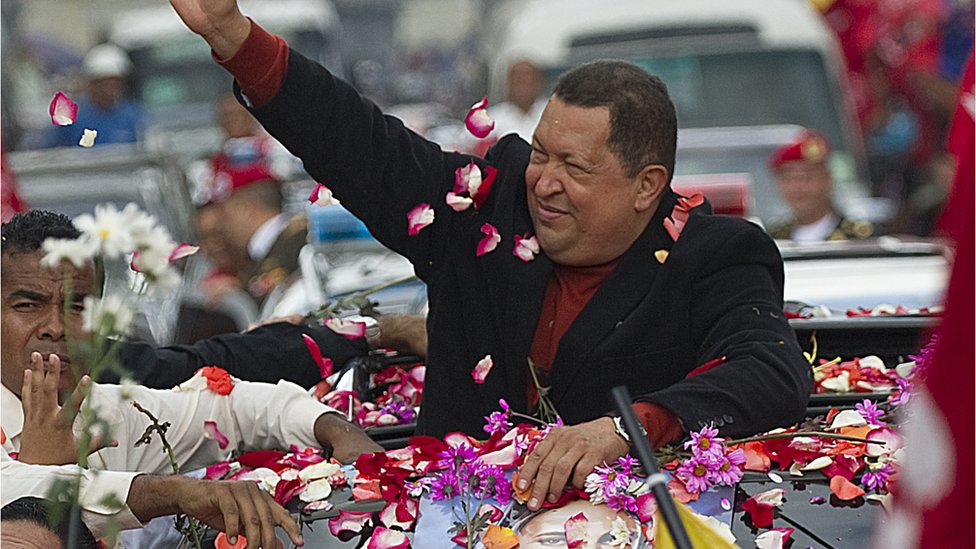 Hugo Chávez is covered in flower petals by supporters as he rides in an open-topped car in 2012.