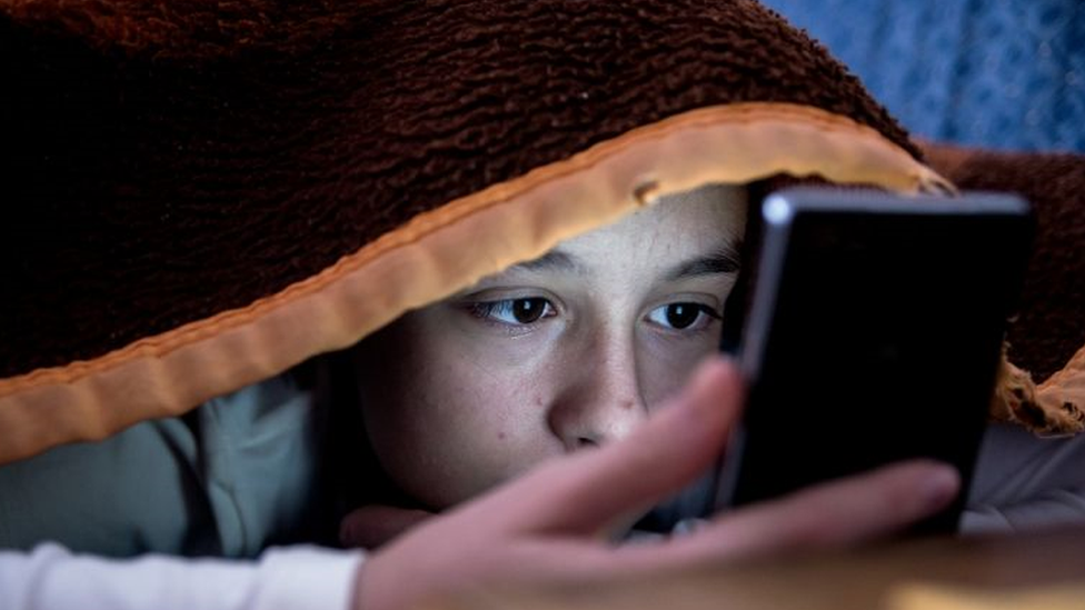 Dois adolescentes, menino e menina, jogam jogo para celular em smartphones