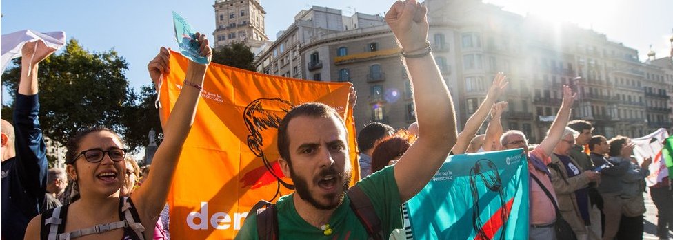 Protesters with 'democracy' flags chant outside the Catalan economy ministry