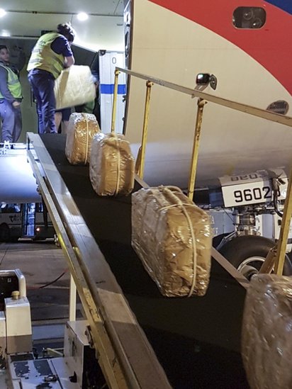 Valijas son transportadas hacia el interior del avión. (Foto: AFP/Ministerio de Seguridad de Argentina)