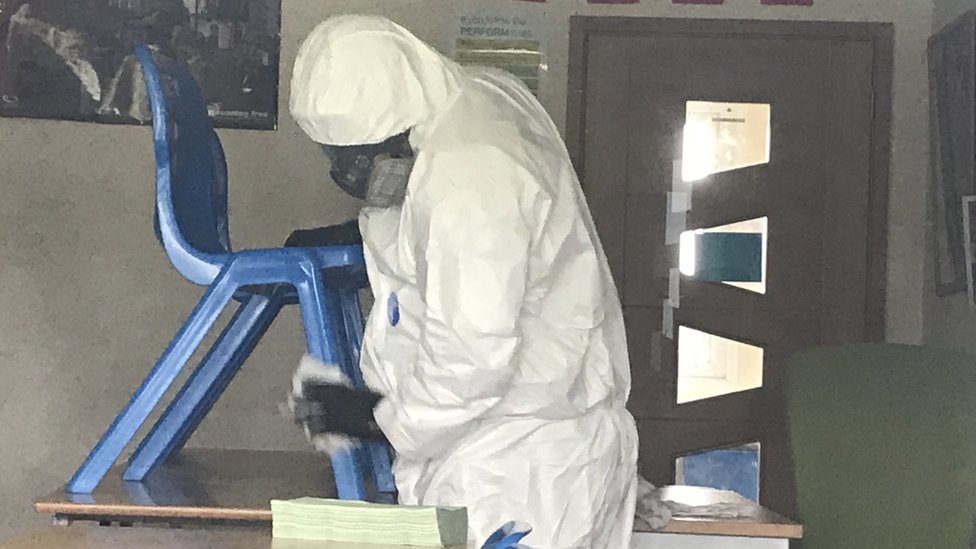 Person in full PPE cleaning a school chair