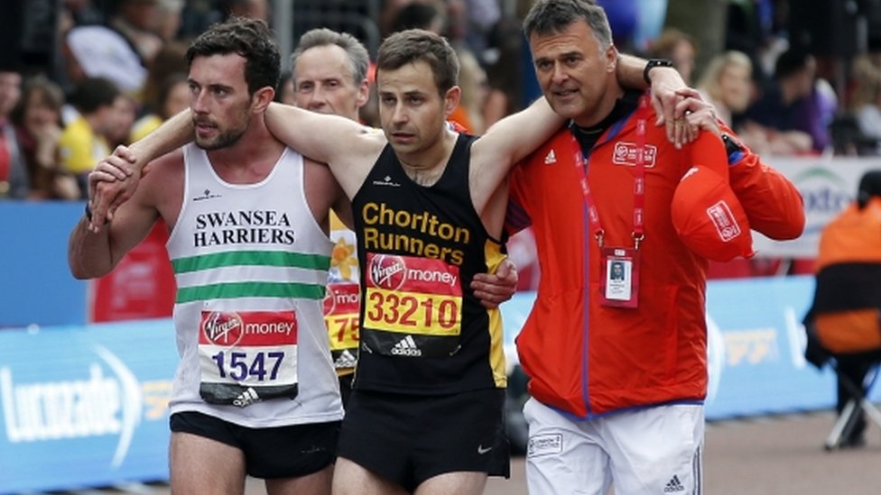 Matthew Rees ayuda a David Wyeth, junto a un oficial de la organización, a cruzar la meta en la maratón de Londrés