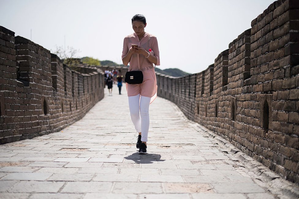 A Chinese lady walks as she types on her smartphone on the Great Wall in Mutianyu, near in Beijing on 23 April 2016.