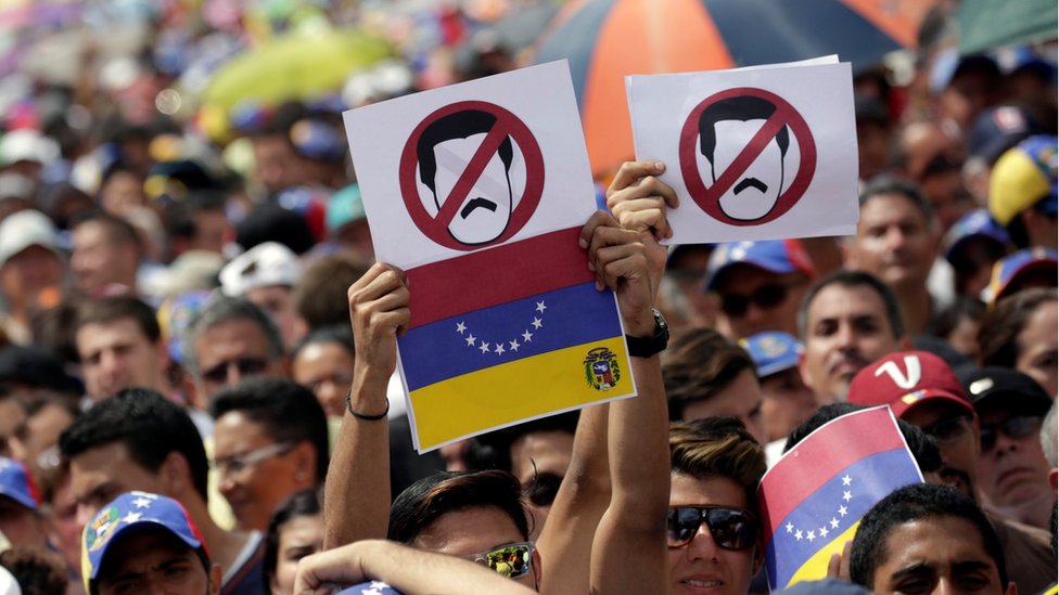 Manifestantes con pancartas contra Maduro.
