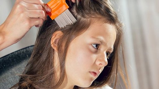 Madre peinando a su hija con un peine especial para piojos
