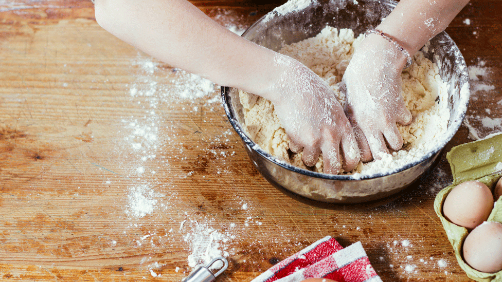 Hands in bowl of dough