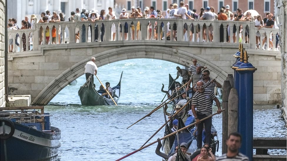 Gondoliers proceed slowly near the Sospiri Bridge near St Mark's Square due to too much traffic, 2 August 2023