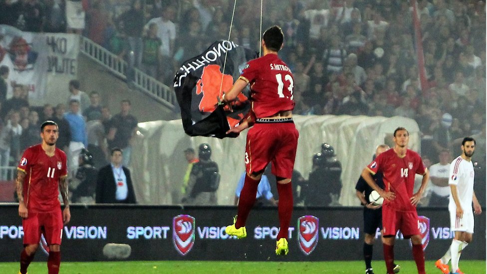 Serbia defender Stefan Mitrovic grabs flag suspended from drone on 14 Oct 2014