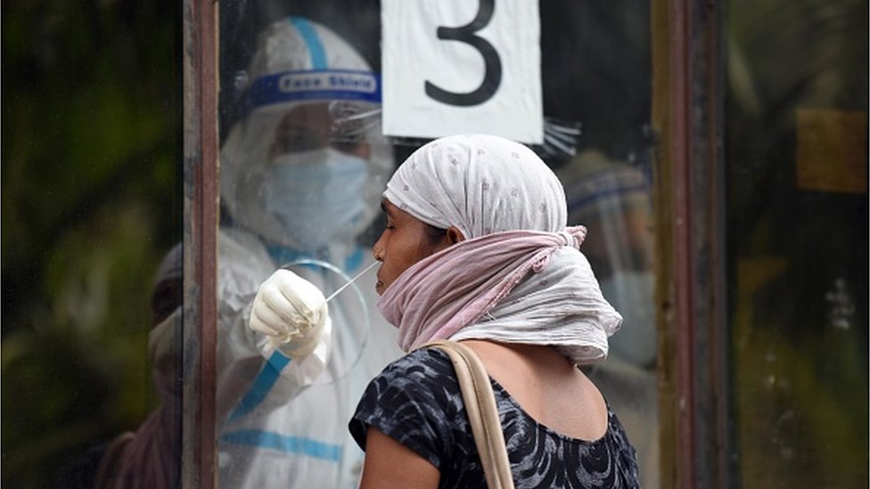 A health worker collects a swab sample from a woman for Covid-19 rapid antigen test in New Delhi, India