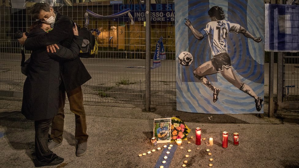 Люди обнимаются после смерти легенды аргентинского футбола Диего Марадоны возле стадиона Сан-Паоло в Неаполе, Италия