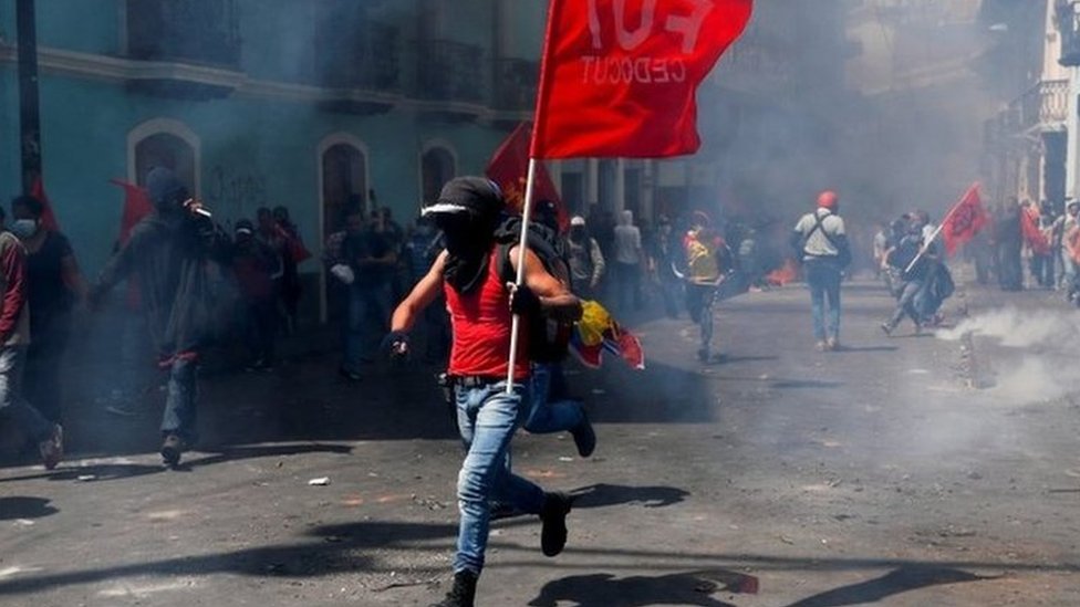Протестующий бежит по улицам, размахивая красным флагом
