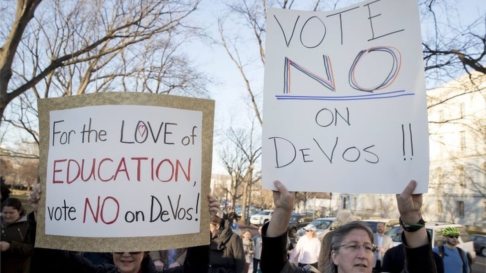 Люди держат плакаты во время митинга, призывающего Сенат США проголосовать против утверждения Бетси ДеВос, кандидатуры президента Дональда Трампа на пост министра образования.