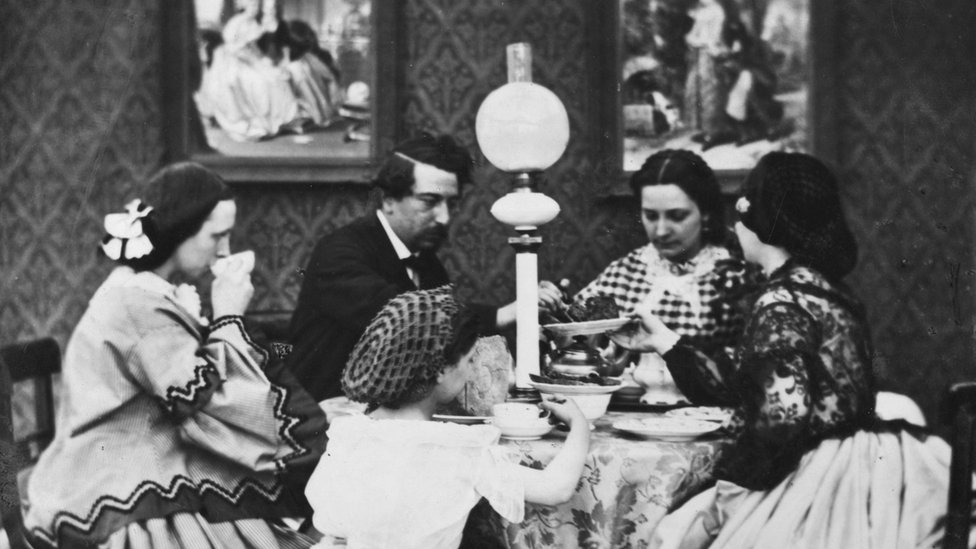 La electrificación de los hogares cambió los hábitos de sueño de las personas. Una familia ante una mesa con luz eléctrica en una vivienda en el siglo XIX.