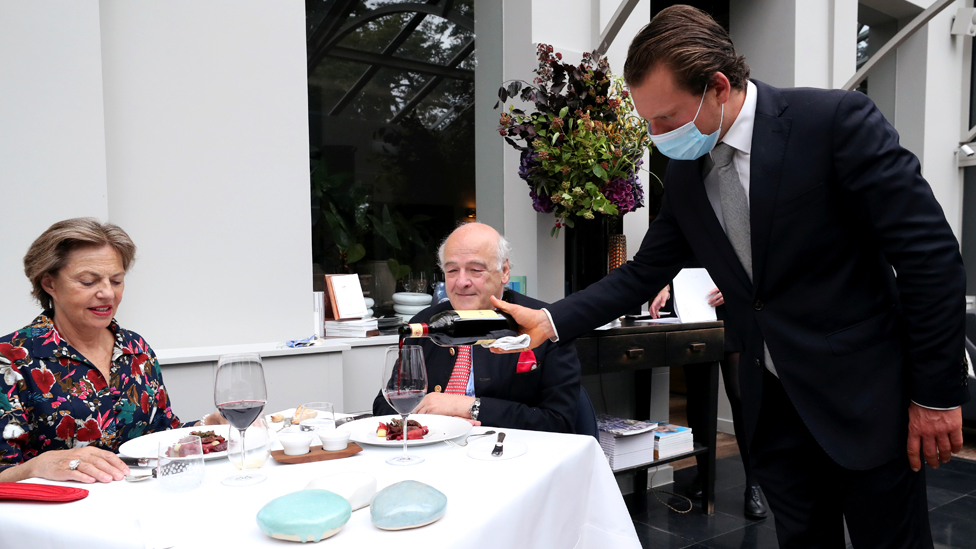 Customers are poured wine by a waiter wearing a mask in Belgium