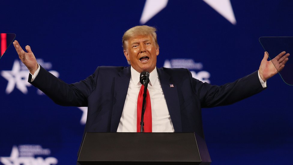 Former President Donald Trump gestures with open arms at a conference in February