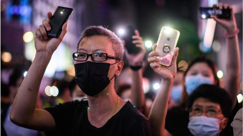 كيف أصبحت التكنولوجيا الحديثة سلاحا ذا حدين لمظاهرات آسيا؟ 1 Pro-democracy protesters hold up their mobile phone torches as they sing during a rally in the Causeway Bay district of Hong Kong on June 12, 2020