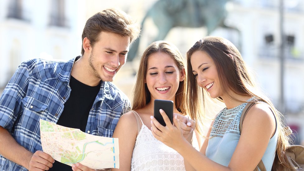 Los servicios de GPS se activan en muchas aplicaciones aunque no nos demos cuenta. Grupo de 3 jóvenes con mapa y celular