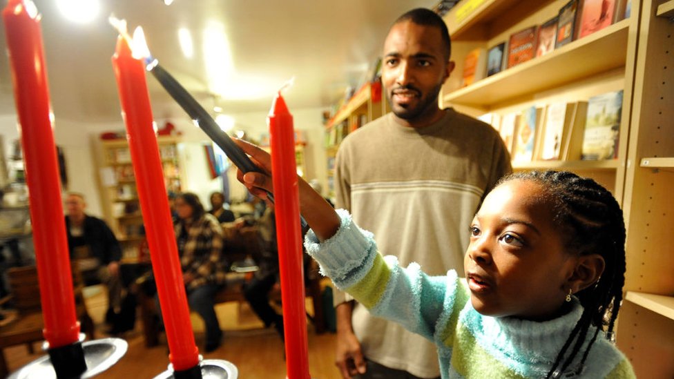 Gerard Greenige enciende velas con su hija Asha, de 4 años, durante la celebración de Kwanzaa en Long Beach, California, el 26 de diciembre de 2008.