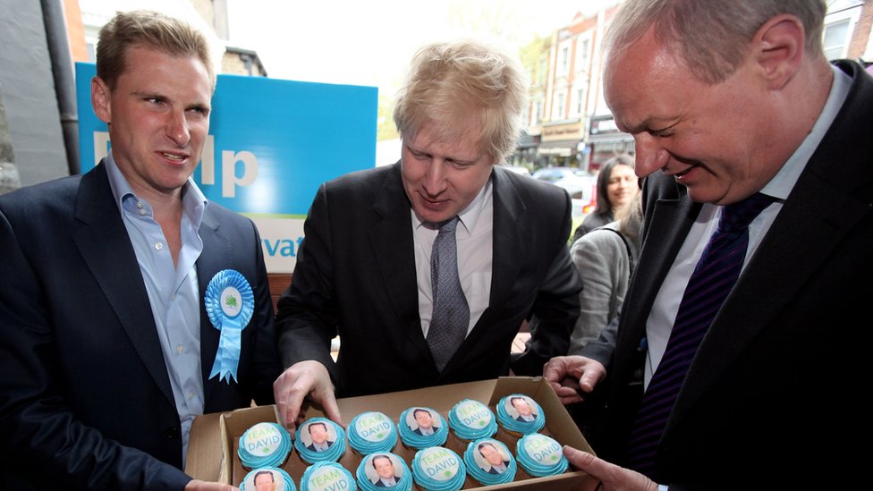 Крис Филп (слева), кандидат от консервативной партии на пост Хэмпстеда, Борис Джонсон и депутат от консерваторов Дэмиан Грин (справа) наслаждаются кексами Дэвида Кэмерона (фото от апреля 2010 г.)