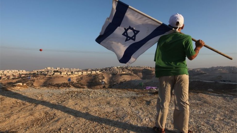Jewish youth holds Israeli flag near Jewish settlement of Maale Adumim (file photo)