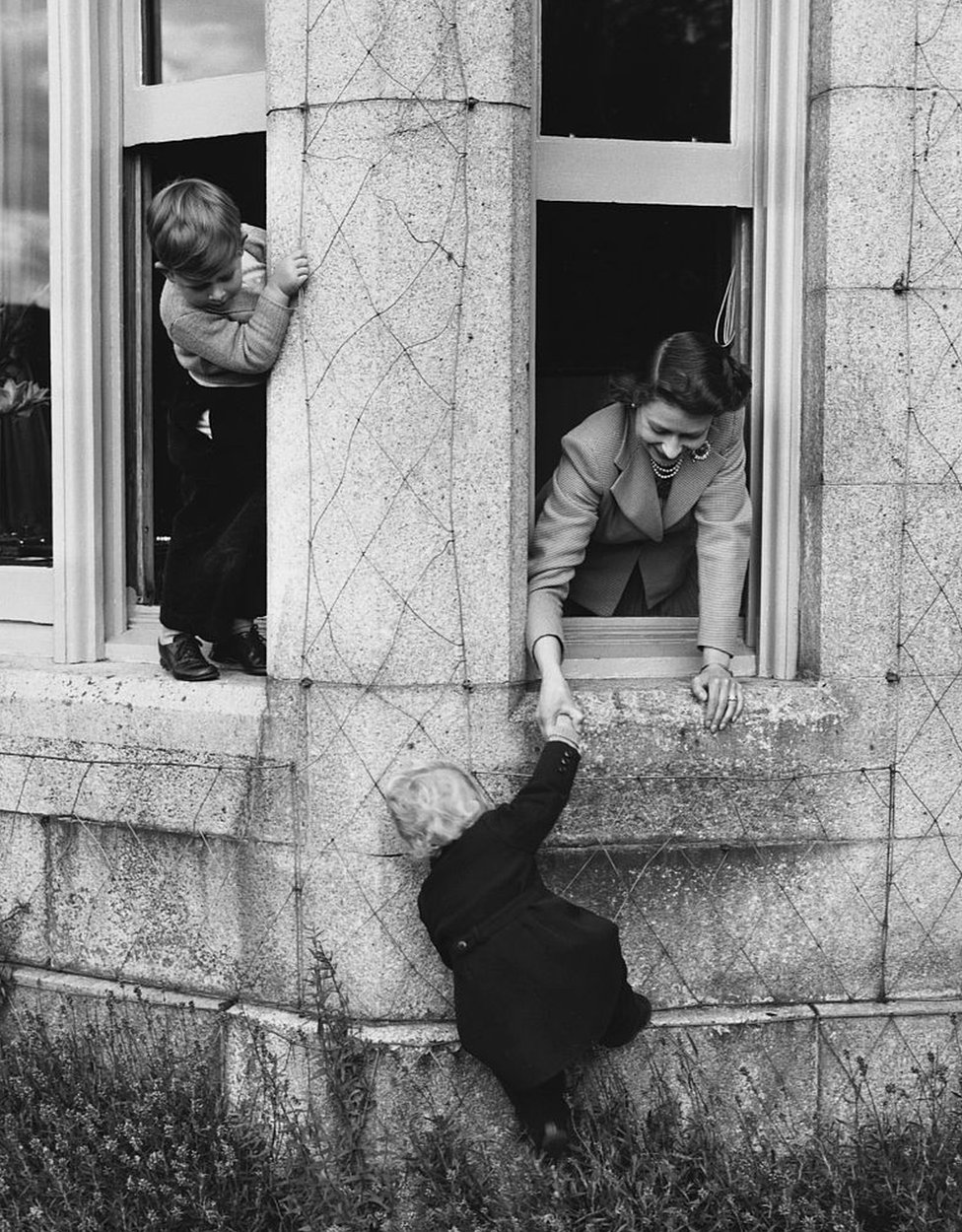 La reina juega con el príncipe Carlos y la princesa Ana en las ventanas del castillo en 1952.