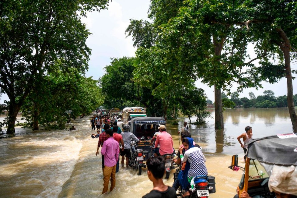 Жители Индии едут на своих машинах по затопленной дороге после сильных муссонных дождей в районе Ситамархи в индийском штате Бихар.