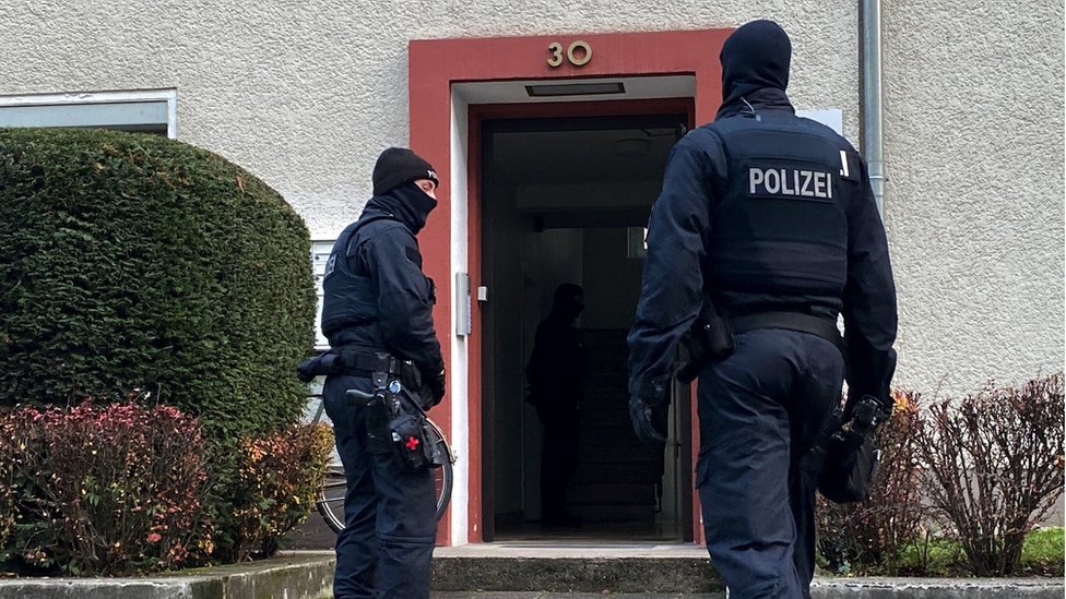 Fotografia de policiais em frente a uma porta