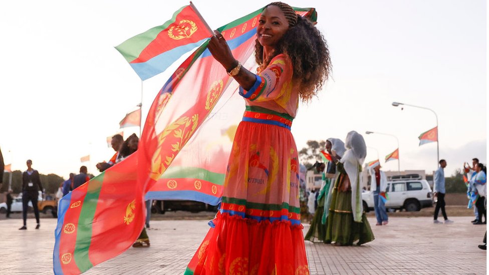 امرأة ترتدي ألوان العلم الإريتري وتحمل العلم الإريتري.