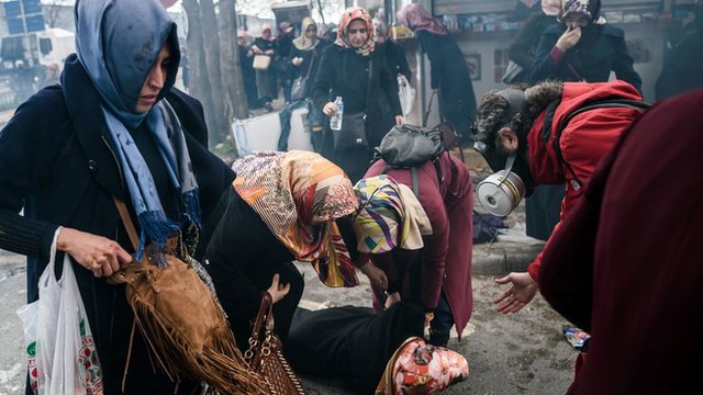Women helps another woman who felt as Turkish anti-riot police officers use tear gas to disperse supporters in front of the headquarters of the Turkish daily newspaper Zaman in Istanbul on March 5, 2016