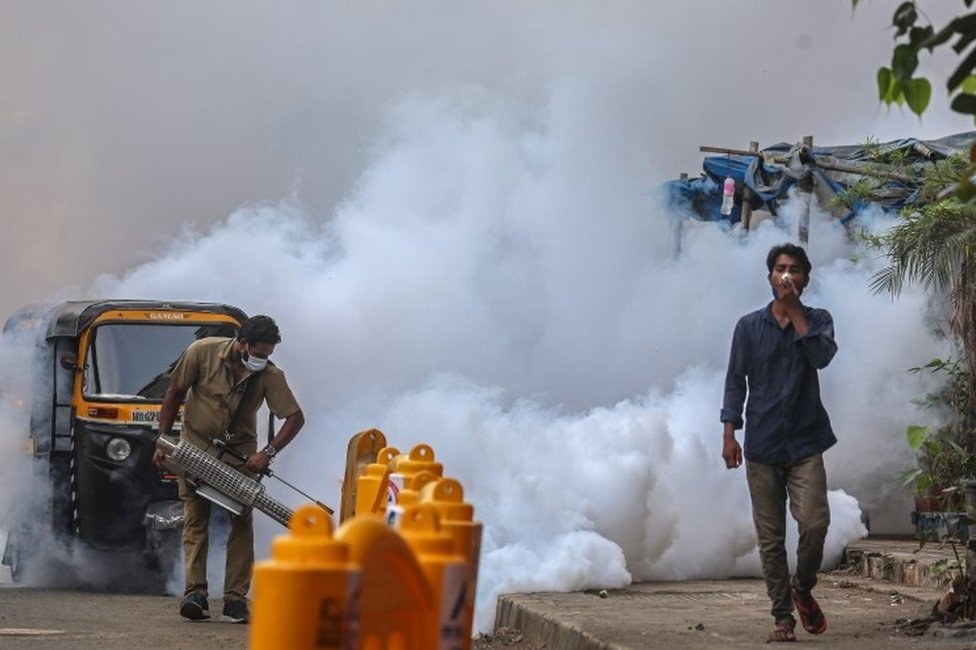 Um trabalhador municipal usando uma máscara facial usa máquina de spray de fumigação perto de um centro de vacinação em Mumbai, Índia, 30 de abril de 2021