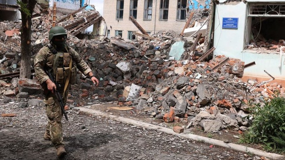 A Ukrainian serviceman passes by destroyed buildings in the Ukrainian town of Siversk, Donetsk region on July 22, 2022