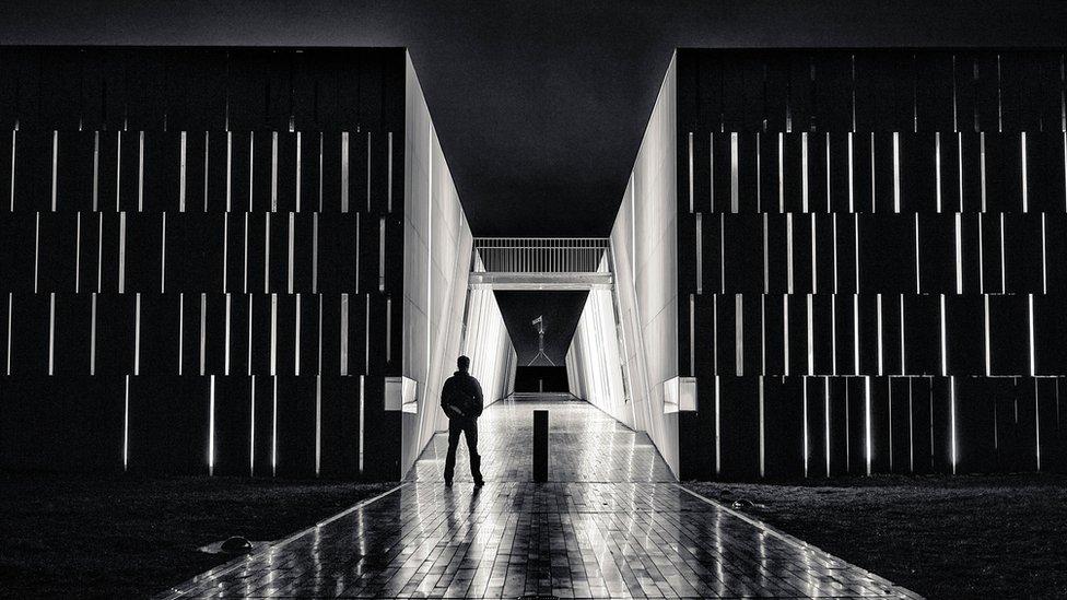 Una image en blanco y negro de un hombre con el Parlamento australiano al fondo.