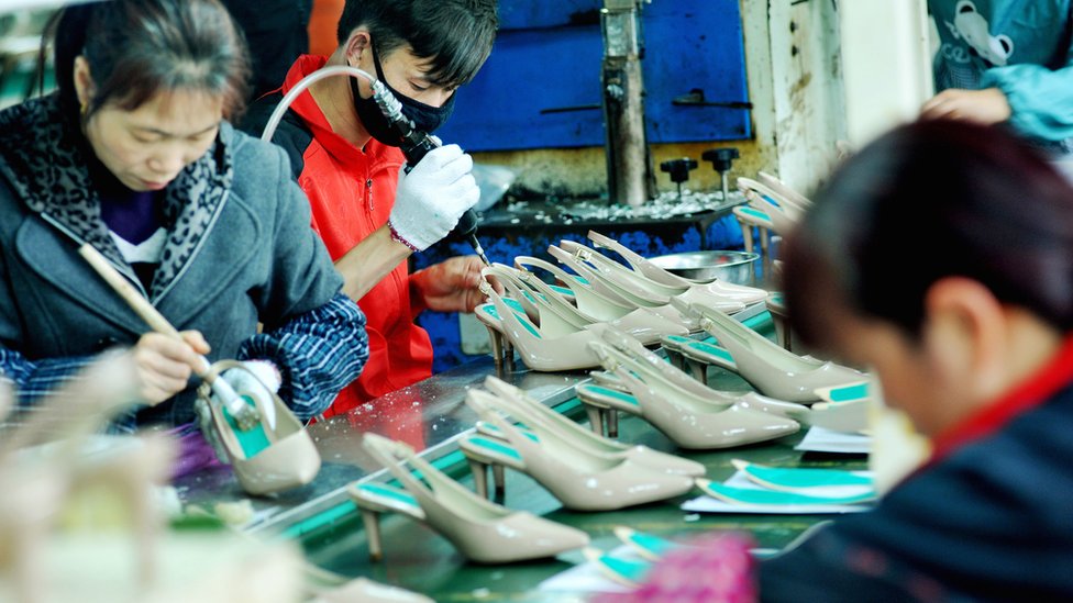 На этой фотографии, сделанной 25 марта 2018 года, показаны китайские сотрудники, производящие обувь на экспорт на фабрике в Шанграо, в центральной провинции Китая Цзянси.