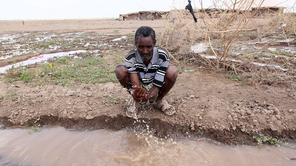 Мужчина моет руку проточной водой из выкопанной траншеи в пострадавшем от засухи районе Сомали в Эфиопии, 26 января 2016 года.
