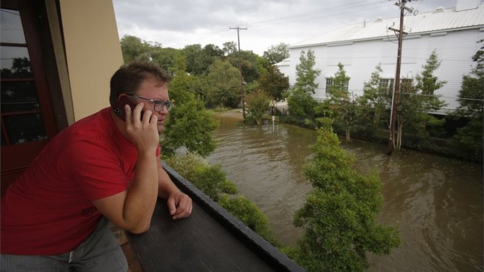 Un hombre habla por teléfono mientras observa la calle inundada