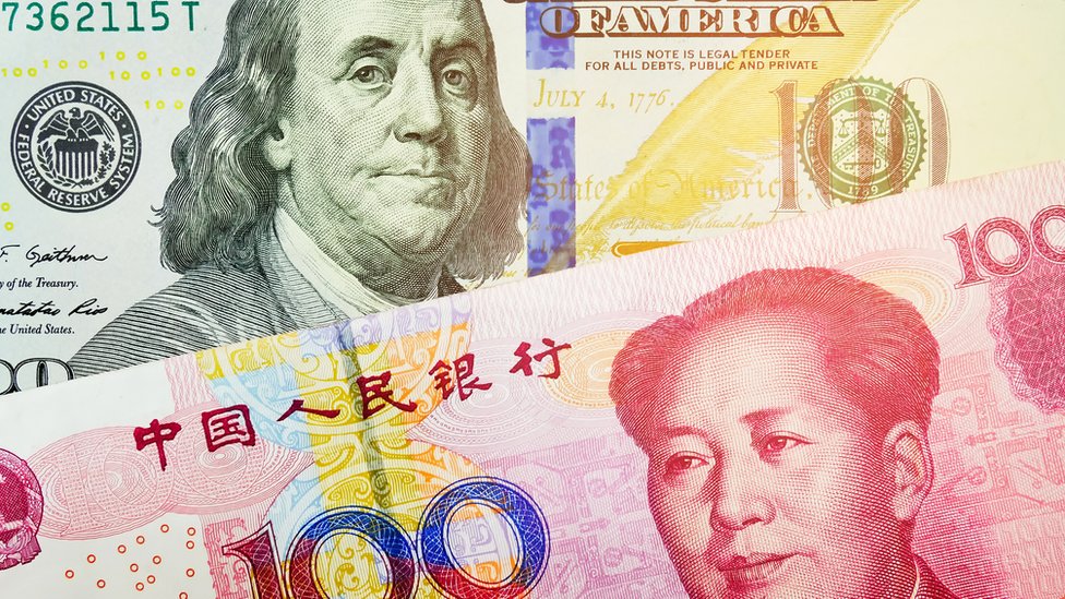 Un billete de 100 dólares y otro de 100 yuanes chinos.