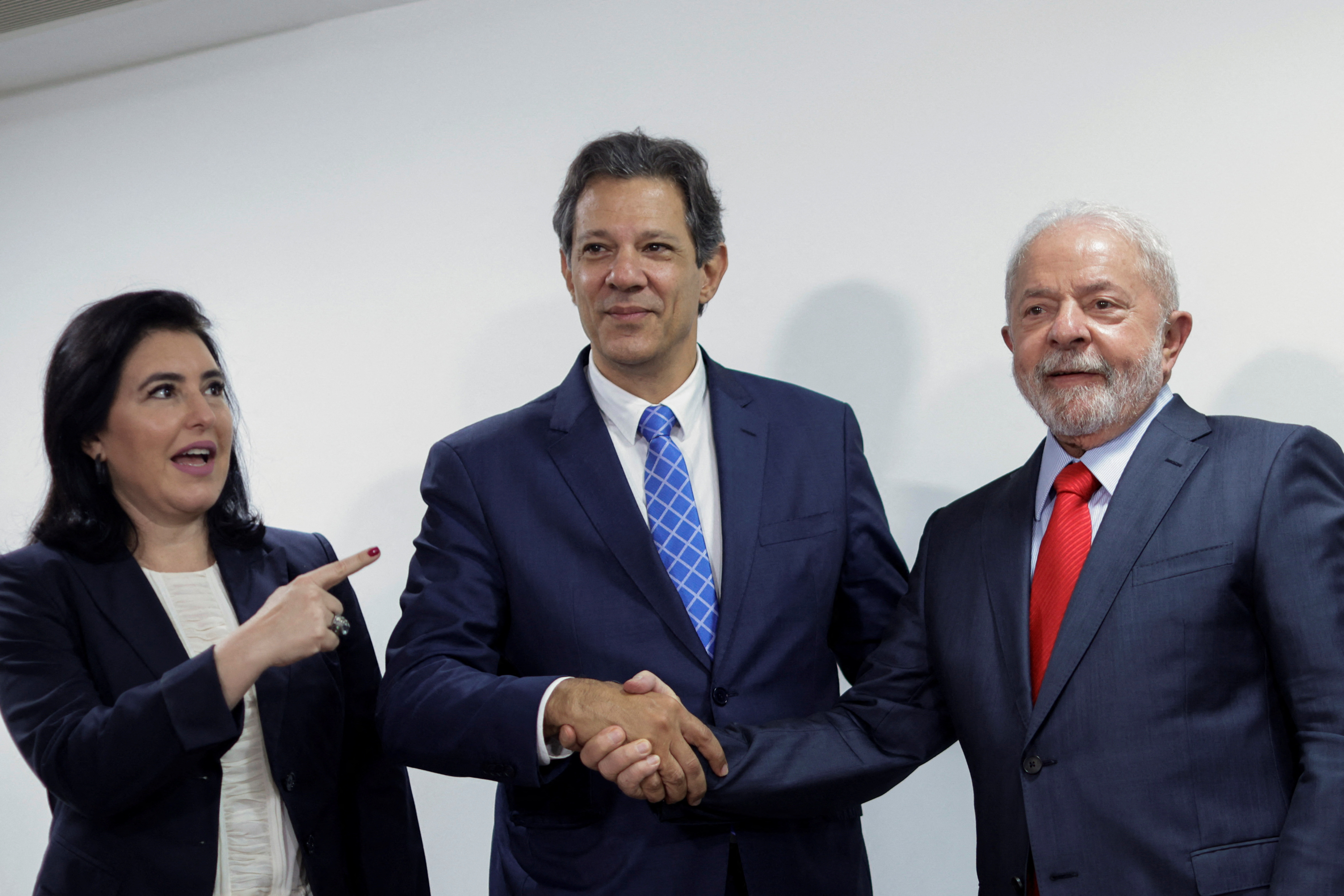 Fernando Haddad, ao lado de Simone Tebet, cumprimenta Lula; todos com expressão de felicidade