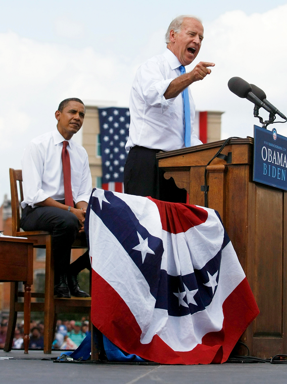 Barak Obama listens to Joe Biden on stage