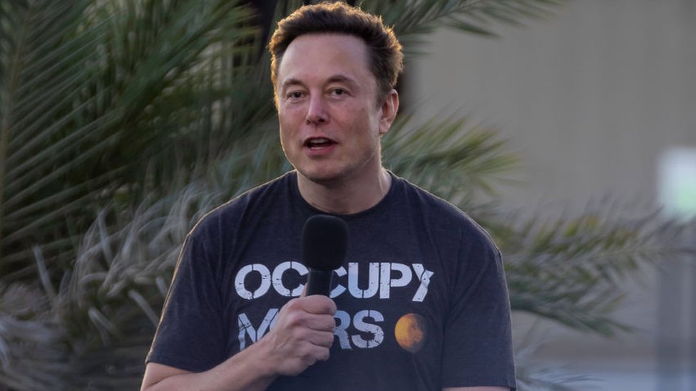 Elon Musk segurando um microfone