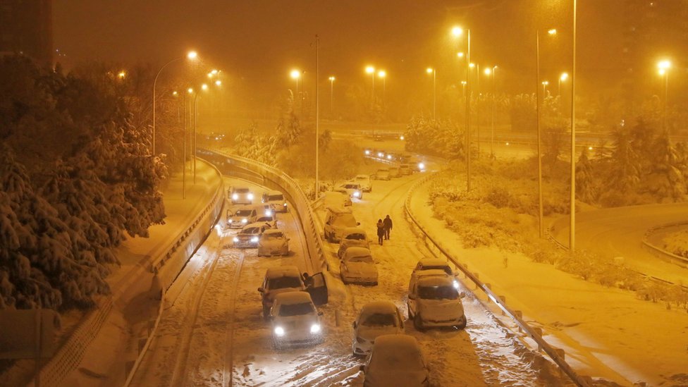 People walk after leaving their vehicles on a road in Madrid