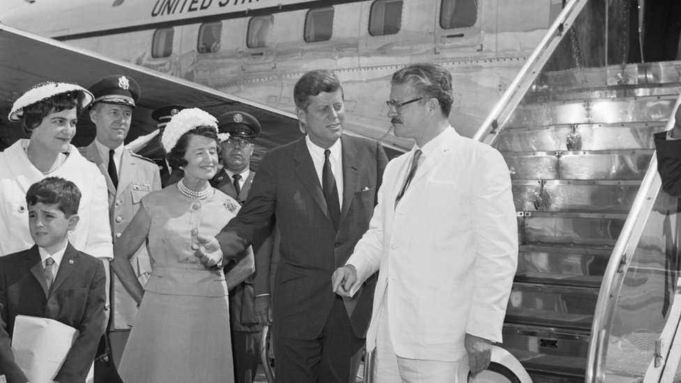 Президент Кеннеди болтает с президентом Эквадора Хулио Аросемена (крайний справа), когда они позируют оператору в Национальном аэропорту Вашингтона, июль 1962 г.