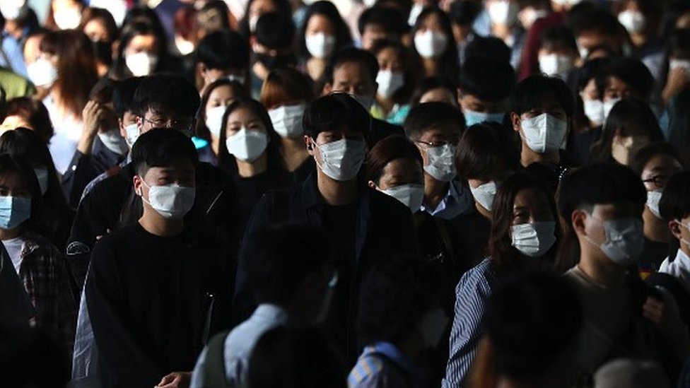 People walking along a street wearing masks