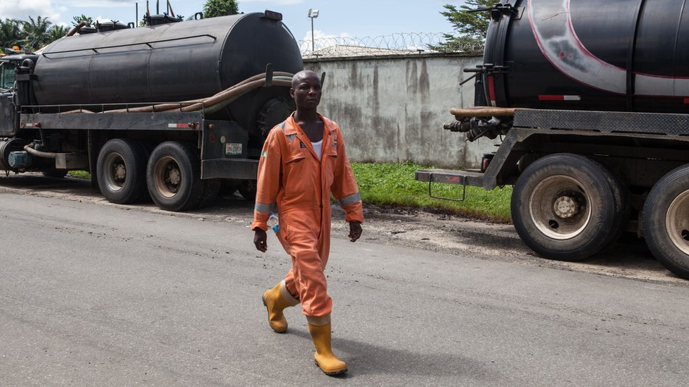 Сотрудник проходит мимо грузовиков с нефтью в Порт-Харкорте в Нигерии.
