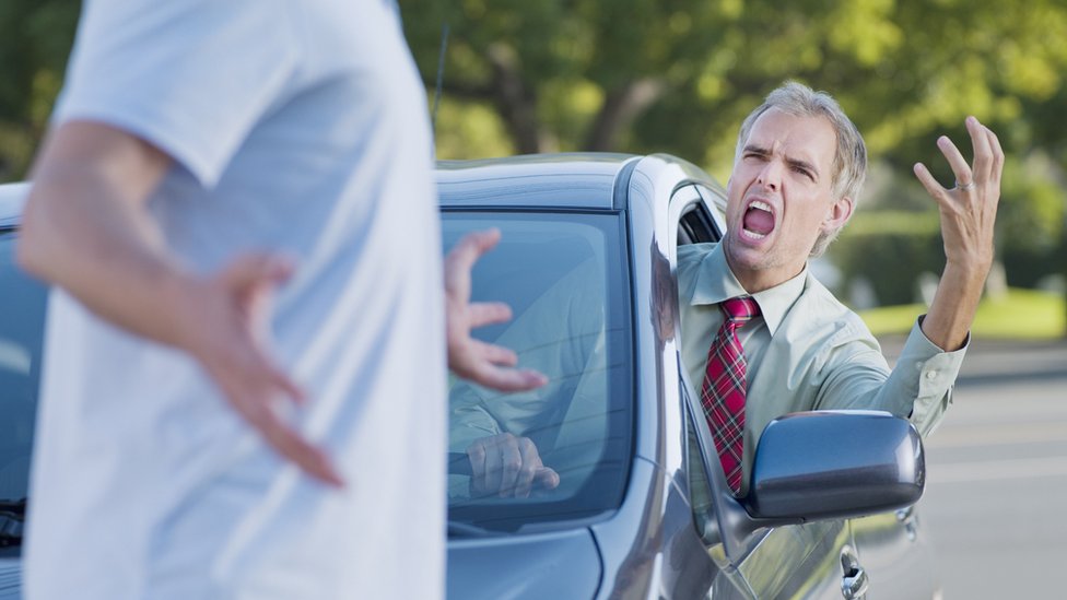 An angry driver shouting at a pedestrian crossing the road