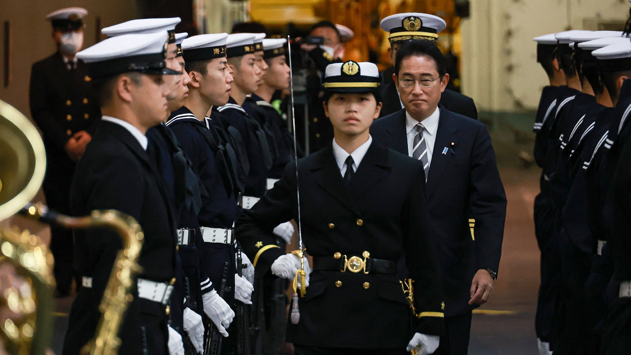Japan's Prime Minister Fumio Kishida (centre R-facing) receives an honorary salute aboard the Japanese helicopter carrier JS Izumo during an 
